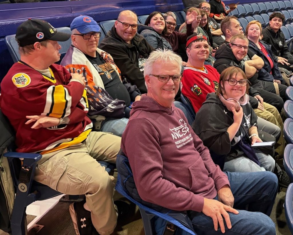 Staff member with group of participants at Chicago Wolves hockey game